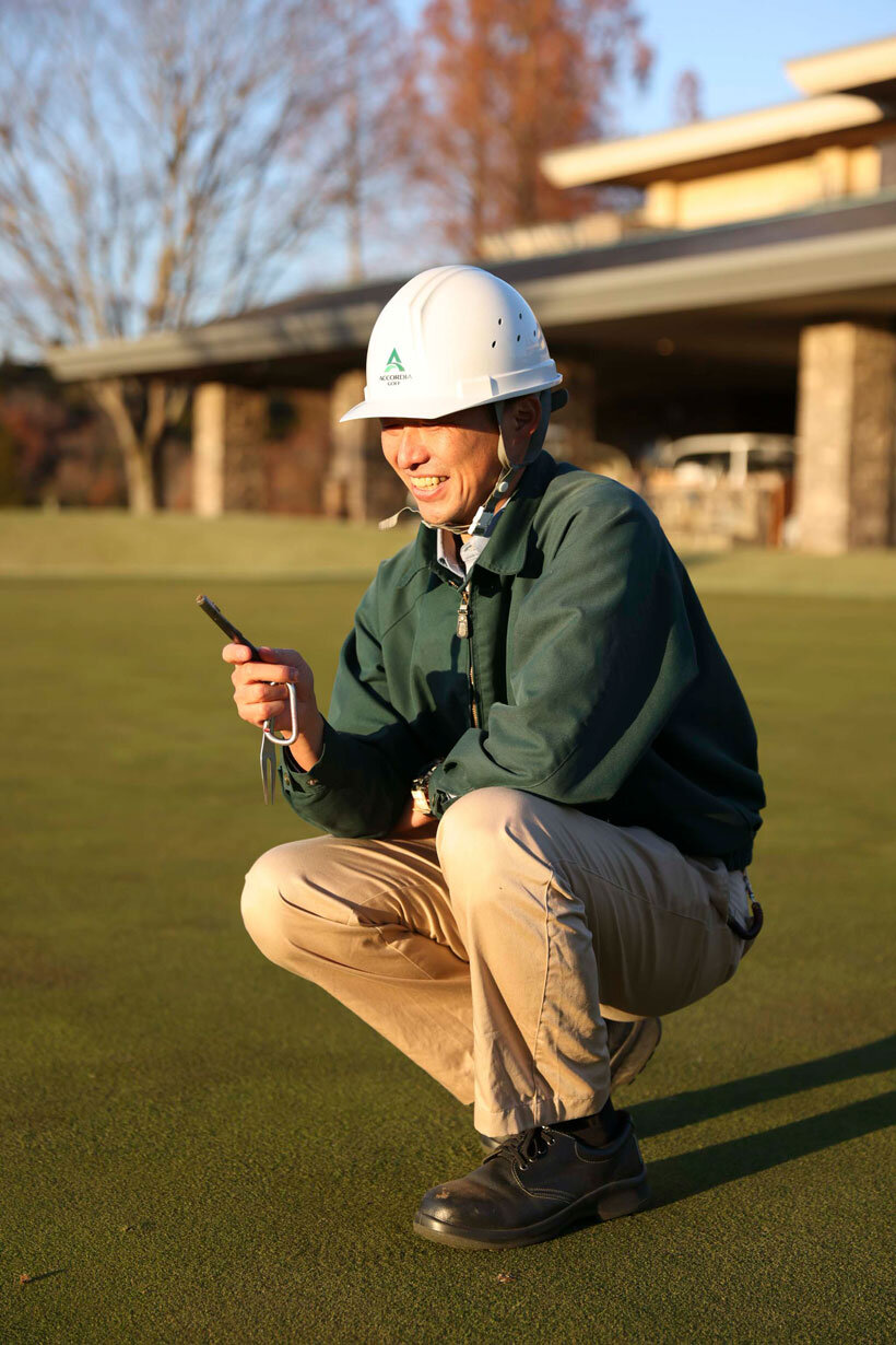グリーンの芝の状態を確認するスタッフ